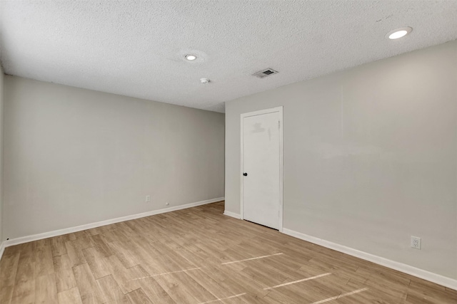 spare room with a textured ceiling and light hardwood / wood-style flooring