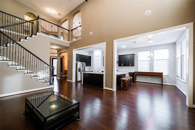 entrance foyer featuring sink, a towering ceiling, dark wood-type flooring, and a notable chandelier