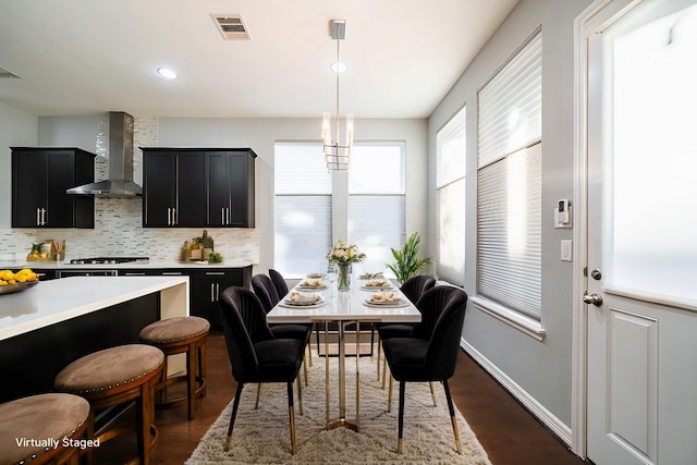 kitchen with dark hardwood / wood-style flooring, backsplash, wall chimney exhaust hood, hanging light fixtures, and stainless steel gas stovetop