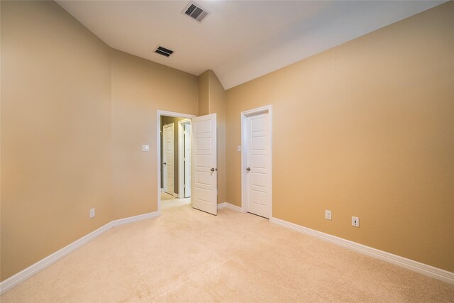 carpeted empty room featuring lofted ceiling