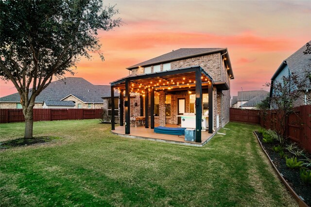 back house at dusk with a yard and a patio