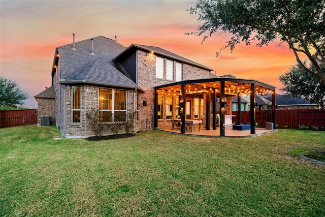 back house at dusk featuring a yard, a patio, and central AC