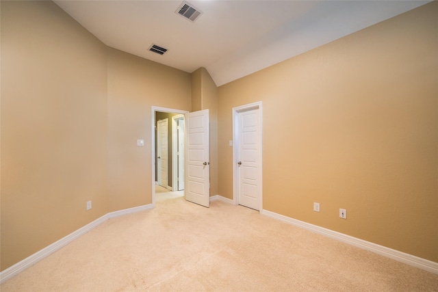 carpeted empty room featuring lofted ceiling