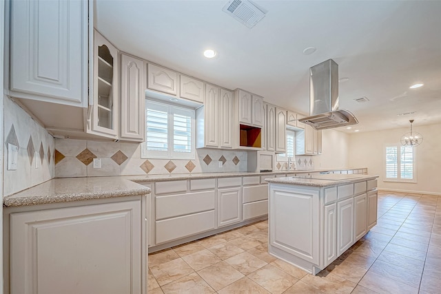 kitchen with white cabinetry, a center island, backsplash, decorative light fixtures, and island range hood