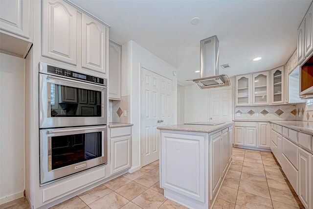 kitchen featuring backsplash, white cabinetry, a center island, and stainless steel double oven