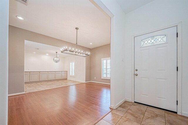 foyer with light hardwood / wood-style flooring and an inviting chandelier