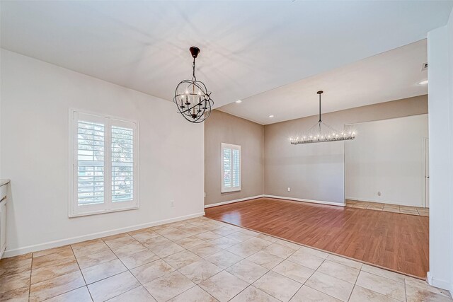 unfurnished dining area featuring an inviting chandelier, a healthy amount of sunlight, and light wood-type flooring