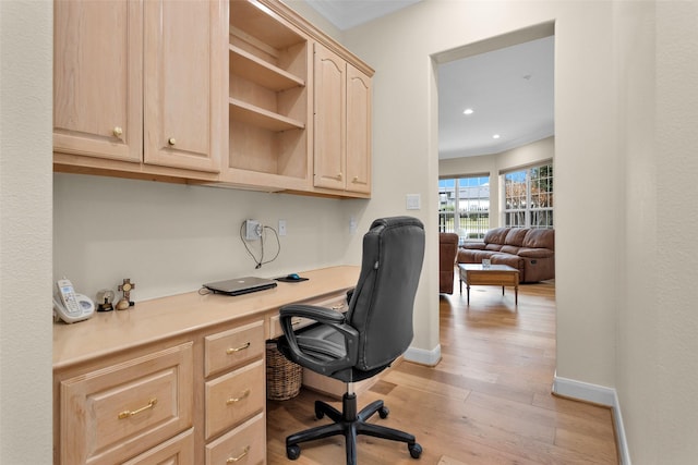 office with built in desk, light hardwood / wood-style floors, and ornamental molding