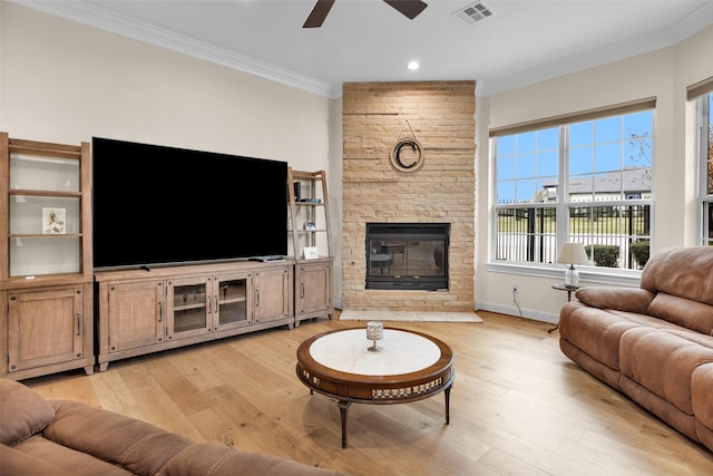 living room with ceiling fan, a large fireplace, crown molding, and light hardwood / wood-style flooring