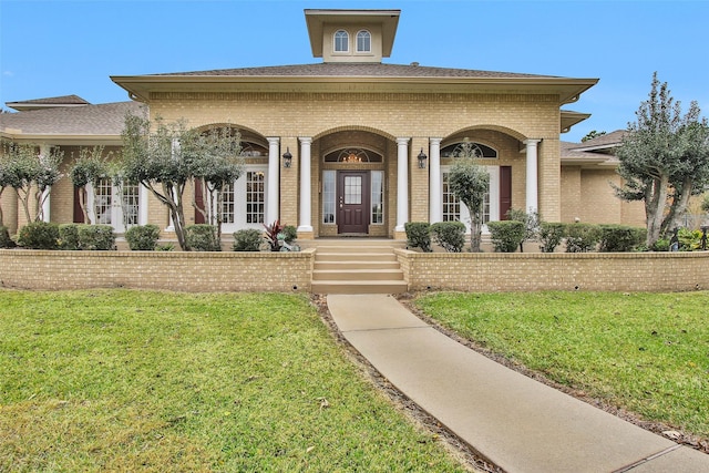 entrance to property featuring covered porch and a yard