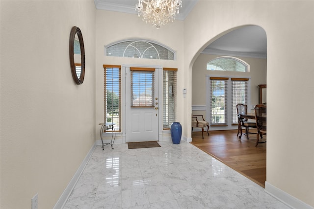 foyer entrance with light wood-type flooring, a notable chandelier, and ornamental molding