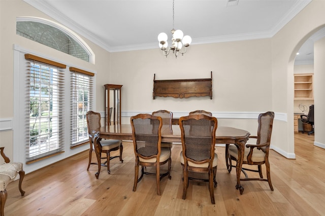 dining area with ornamental molding, light hardwood / wood-style floors, and a notable chandelier