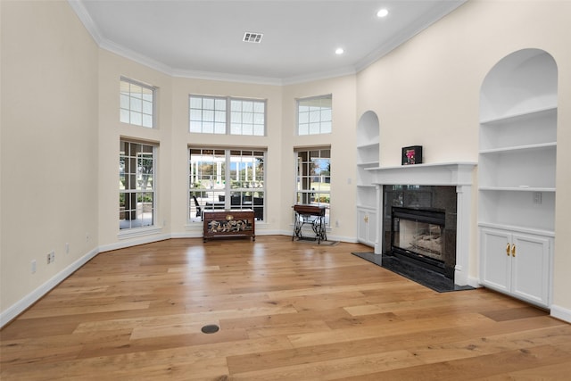 unfurnished living room with light hardwood / wood-style flooring, ornamental molding, and a premium fireplace