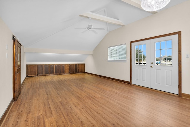 bonus room with a barn door, lofted ceiling with beams, ceiling fan, and light hardwood / wood-style floors