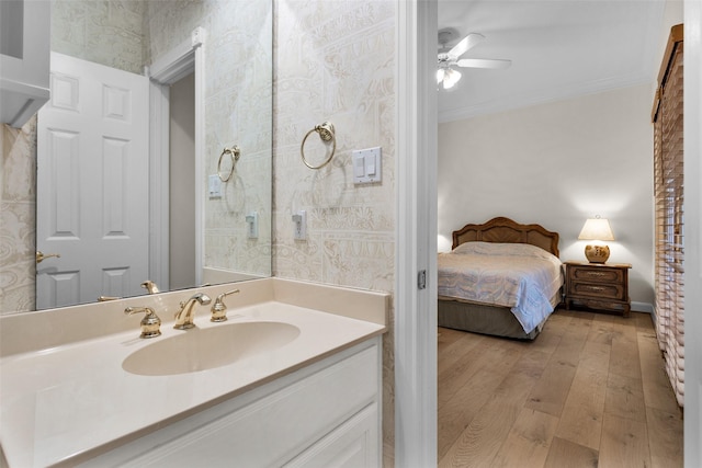 bathroom featuring hardwood / wood-style floors, ceiling fan, ornamental molding, and vanity