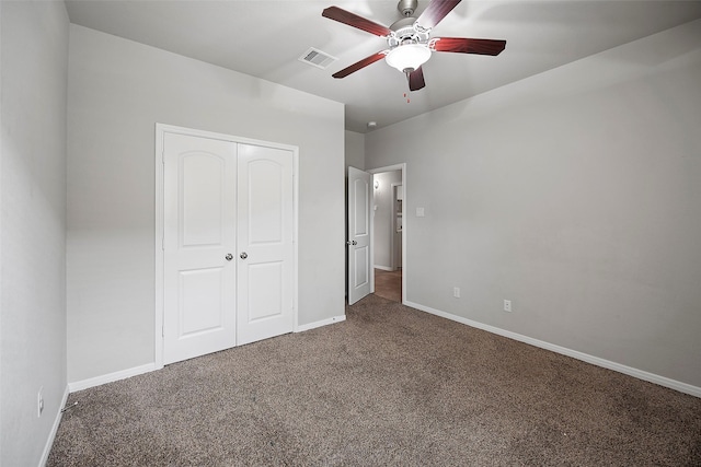 unfurnished bedroom featuring dark colored carpet, a closet, and ceiling fan