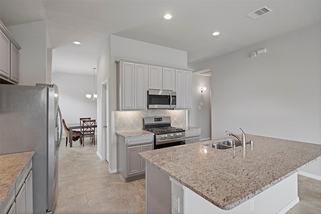 kitchen with sink, stainless steel appliances, tasteful backsplash, gray cabinets, and a kitchen island with sink