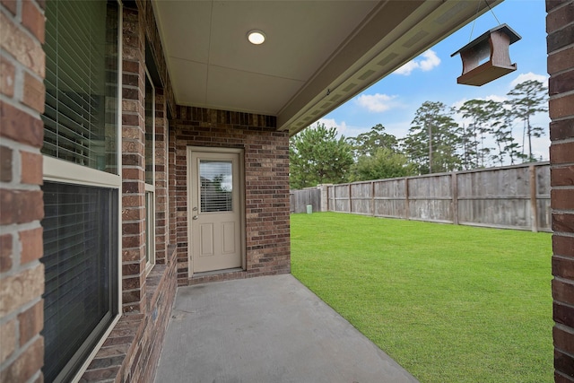 view of exterior entry with a yard and a patio