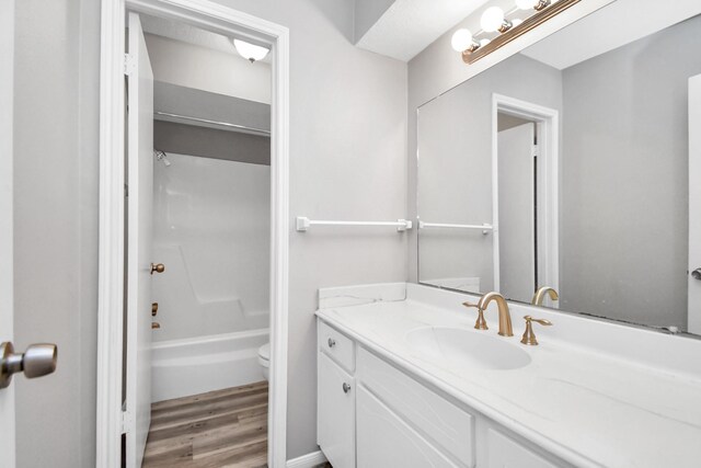 full bathroom with shower / tub combination, vanity, hardwood / wood-style flooring, and toilet