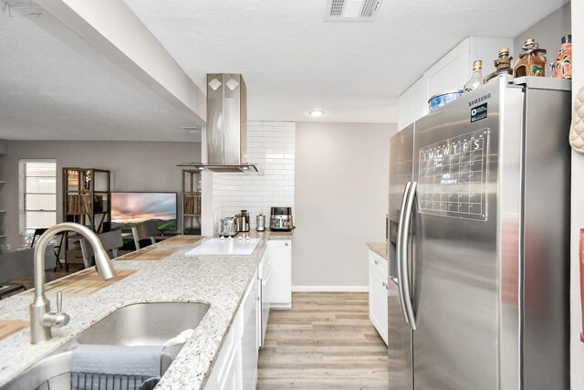 kitchen with light stone countertops, sink, stainless steel fridge with ice dispenser, light hardwood / wood-style floors, and island range hood