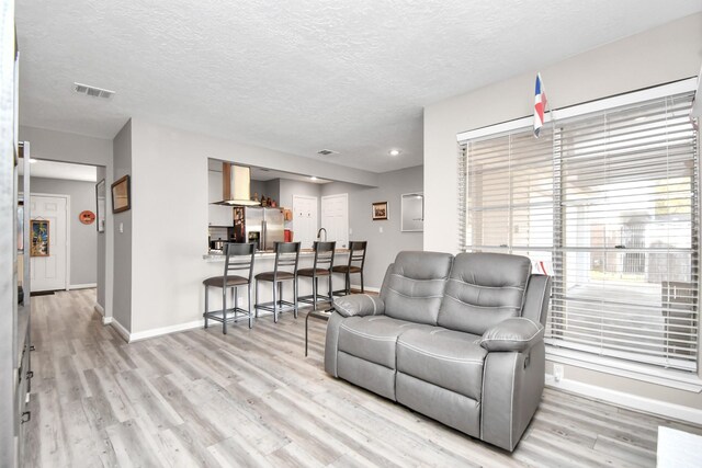 living room with light hardwood / wood-style floors and a textured ceiling