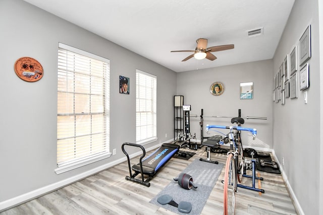 workout room with ceiling fan and light wood-type flooring