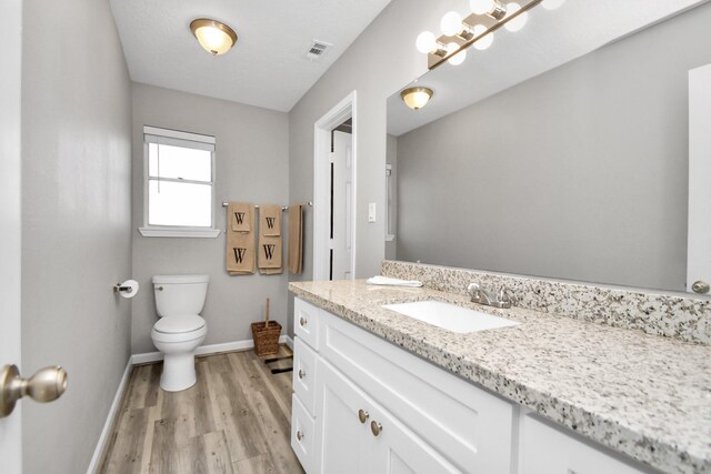 bathroom featuring vanity, hardwood / wood-style flooring, and toilet