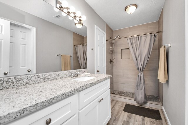 bathroom featuring vanity, curtained shower, wood-type flooring, and a textured ceiling