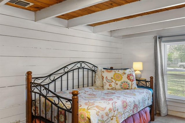 bedroom featuring beam ceiling, wooden walls, and wooden ceiling