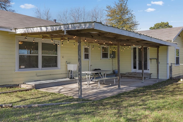 rear view of property with a lawn, a patio area, and sink