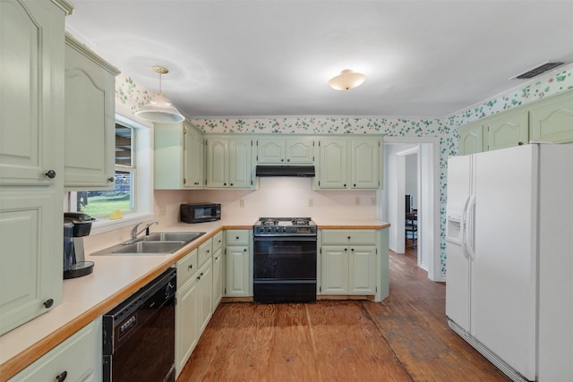 kitchen with sink, black appliances, decorative light fixtures, and hardwood / wood-style flooring