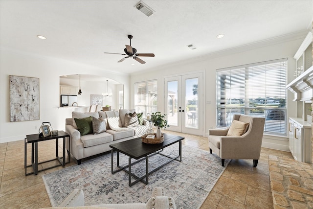 living room with french doors, ceiling fan with notable chandelier, and crown molding