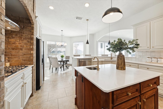 kitchen featuring pendant lighting, a center island with sink, light tile patterned floors, tasteful backsplash, and stainless steel appliances