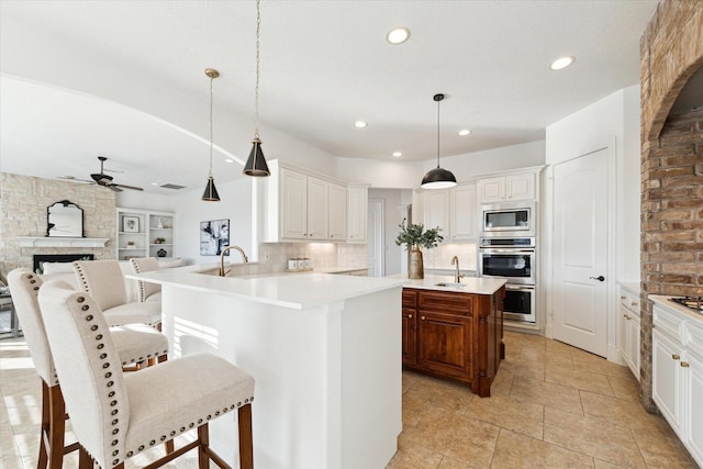 kitchen featuring white cabinets, decorative backsplash, decorative light fixtures, kitchen peninsula, and stainless steel appliances