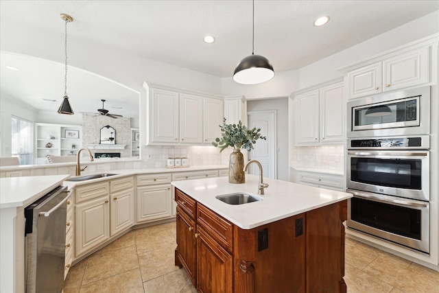 kitchen featuring white cabinetry, sink, decorative light fixtures, a center island with sink, and appliances with stainless steel finishes