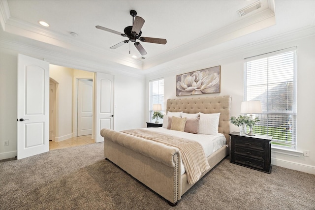 carpeted bedroom featuring a tray ceiling, ceiling fan, and crown molding