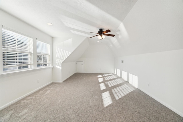 bonus room featuring a textured ceiling, ceiling fan, carpet floors, and lofted ceiling