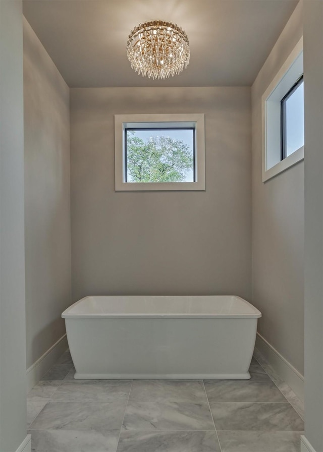 bathroom featuring a tub to relax in and an inviting chandelier