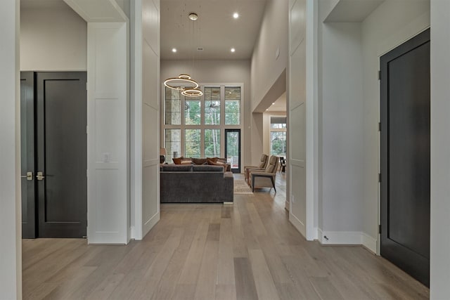 hall featuring a towering ceiling and light hardwood / wood-style floors