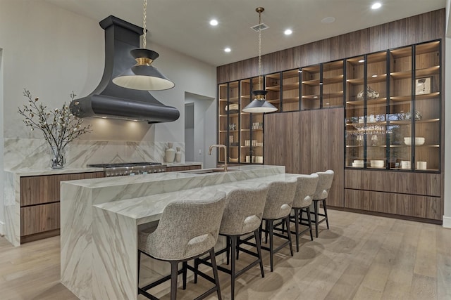 kitchen with light wood-type flooring, tasteful backsplash, stainless steel gas cooktop, and sink