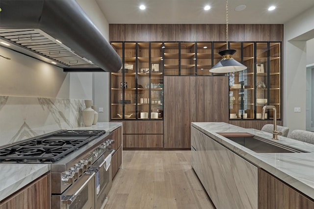 kitchen featuring double oven range, sink, hanging light fixtures, light hardwood / wood-style floors, and extractor fan