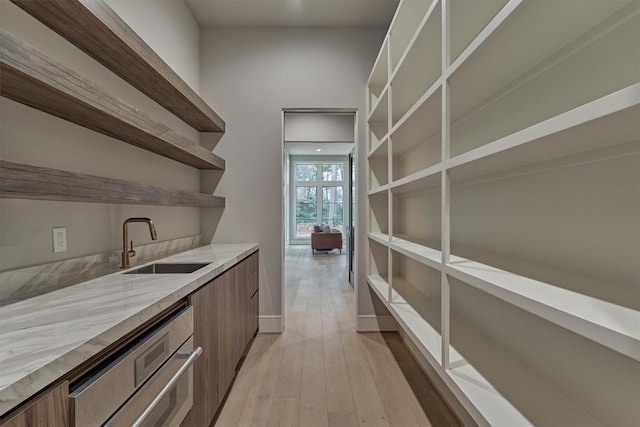 bar with stainless steel appliances, sink, and light hardwood / wood-style flooring