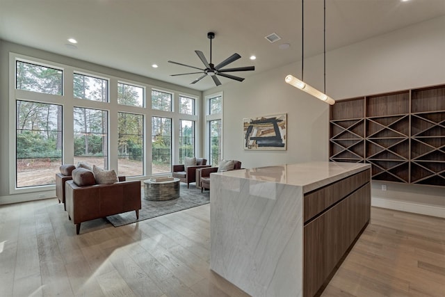 kitchen featuring ceiling fan, light hardwood / wood-style flooring, a center island, and a healthy amount of sunlight