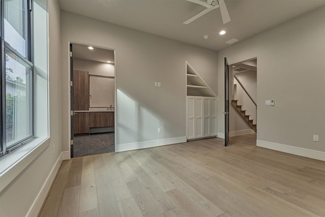 empty room featuring ceiling fan, light wood-type flooring, and a baseboard radiator