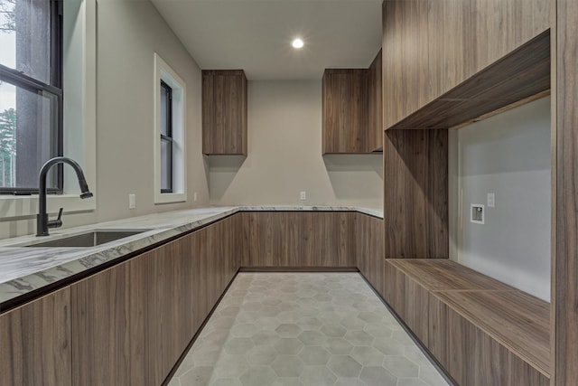 kitchen with light stone counters, sink, and light tile patterned floors