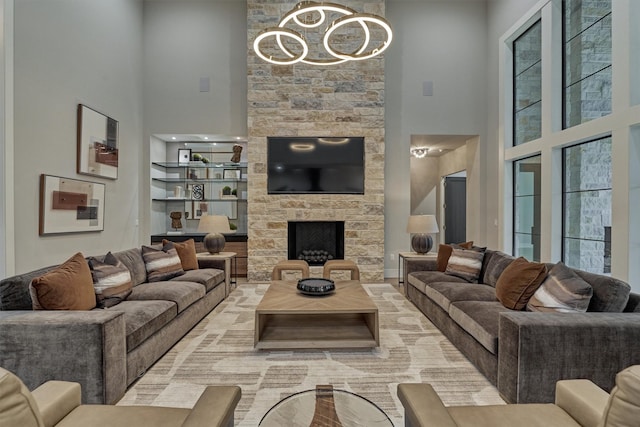 living room with a notable chandelier, a stone fireplace, and a towering ceiling