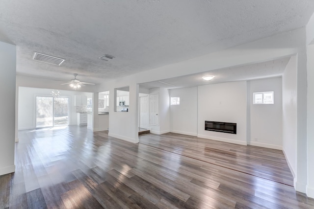 unfurnished living room with a textured ceiling, dark hardwood / wood-style floors, and a healthy amount of sunlight