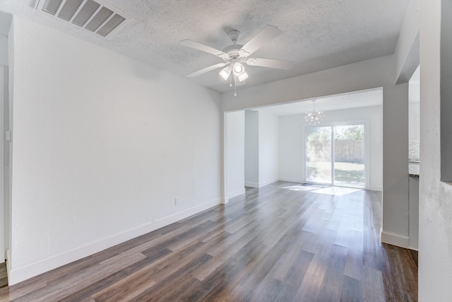 spare room with ceiling fan with notable chandelier, dark hardwood / wood-style flooring, and a textured ceiling