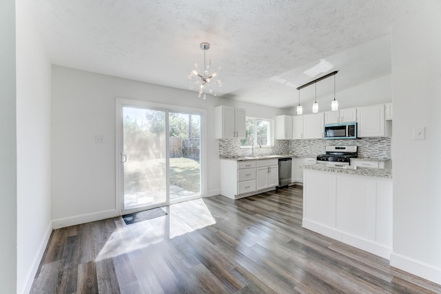 kitchen featuring white cabinetry, hardwood / wood-style floors, pendant lighting, and appliances with stainless steel finishes