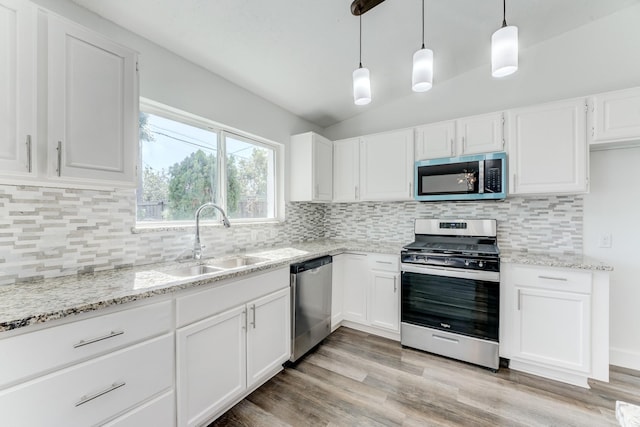 kitchen featuring white cabinetry, sink, stainless steel appliances, lofted ceiling, and decorative light fixtures